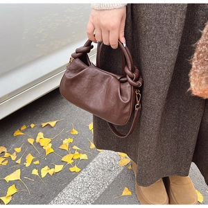 Détail du sac dumpling plissé marron avec poignée nouée et feuilles de ginkgo tombées