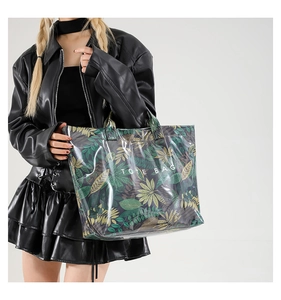 Detail view of large tropical leaf print PVC tote bag with white text on fashion model