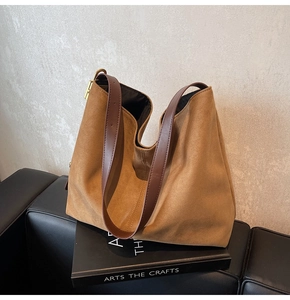 Detailed close-up of large suede tote bag with brown leather straps and gold metal hardware