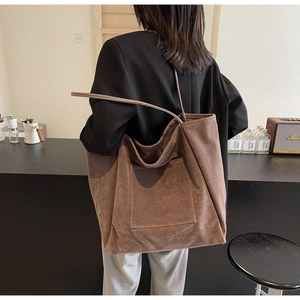 Detailed side view of large brown suede tote bag on a coffee bar counter setting