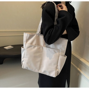Vue portée d'un grand sac fourre-tout en toile beige avec plusieurs poches pratiques