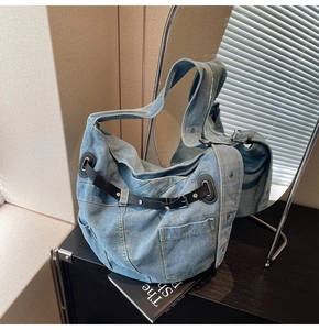 Detail der hellblauen Denim-Umhängetasche mit Lederriemen und funktionellen Taschen