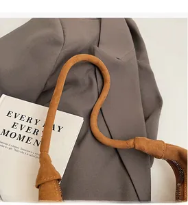 Detail of the thick padded handle and zipper on a brown suede tote bag