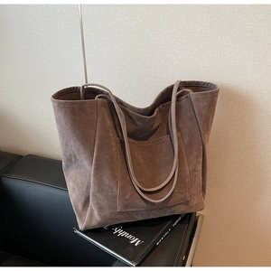 Close-up of brown faux suede large tote bag with front pocket on a black leather seat