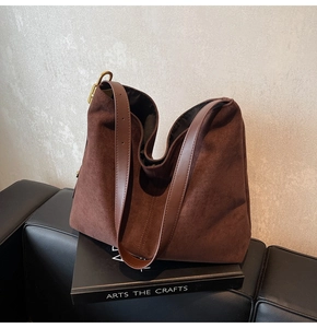 Detailed close-up of dark brown suede bucket bag with gold metal buckle and leather strap