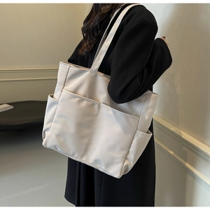 Vue détaillée d'un cabas en nylon beige avec poches fonctionnelles et longue bandoulière