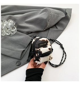 Macro detail of mini PU leather crossbody bag with black and white cow print texture