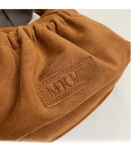 Close-up of MKKM brown suede tote bag showing soft pleated texture and leather logo label