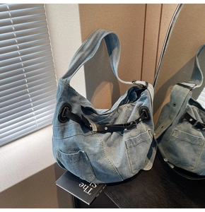 Detail der blauen Denim-Hobo-Tasche mit schwarzen Lederriemen und Nieten im Display