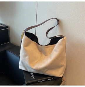 Detail view of large beige suede hobo bag with brown leather strap and gold metal buckle