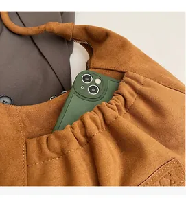 Detail of brown suede crescent bag showing front pocket storage with a smartphone