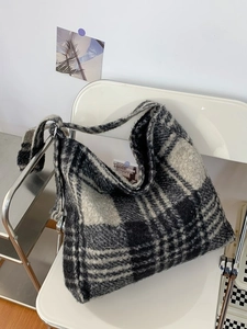 Large black and gray plaid sherpa tote bag displayed on a minimalist white chair