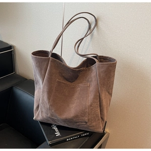 Detailed view of coffee brown suede tote bag with front pocket on a black chair
