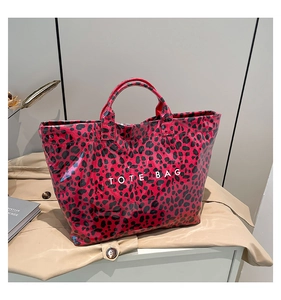 Detail of red leopard print tote bag with white text in a stylish urban lifestyle setting