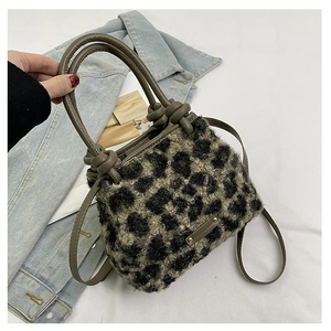 Dettaglio della borsa in peluche leopardata con placca logo e manici marroni