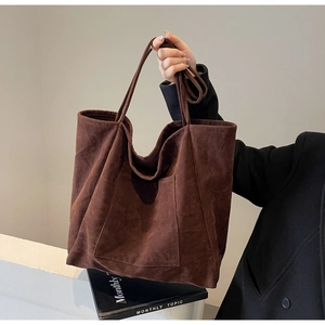Detail of a large dark brown suede tote bag featuring a minimalist square outer pocket