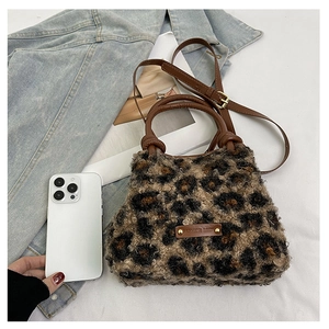 Dettaglio della borsa in peluche leopardata con manici in pelle e dettagli dorati