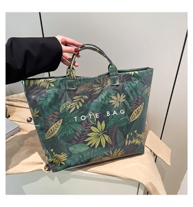 Close-up of a large floral tote bag with leaf pattern and white TOTE BAG text print