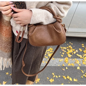 Détail d'un sac nuage plissé marron avec poignées nouées et texte de mode embossé