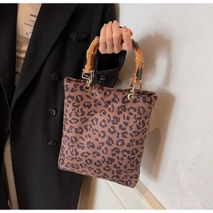 Dettaglio della borsa tote leopardata con manico in bambù e finiture in metallo dorato