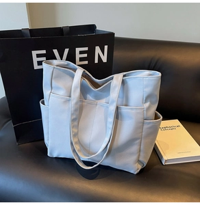 Gros plan d'un grand sac cabas multipoches avec une large bandoulière sur un canapé