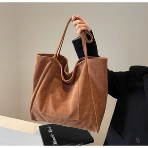 Detail shot of large brown suede tote bag with a front pocket and long handles