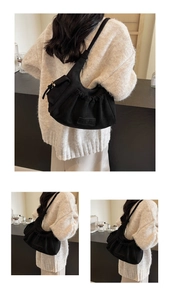 Detail of black pleated tote bag with vintage texture and signature brand label