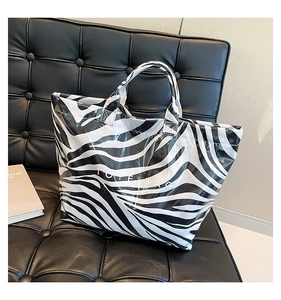Detailed close-up of glossy zebra print tote bag on a modern black leather bench