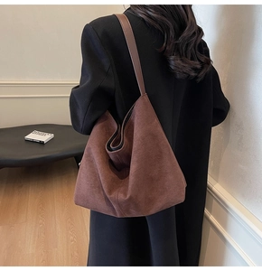 Detailed view of the large caramel suede bucket bag worn over the shoulder by a model