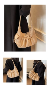 Detail view of beige ruched suede tote bag with MKMX embossed logo and dual zippers
