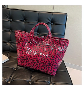 Macro view of hot pink leopard print tote bag with glossy finish on a leather sofa