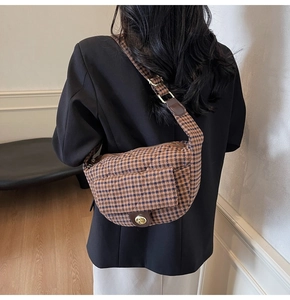 Detail of vintage brown plaid crossbody bag with leather trim and gold metal twist lock