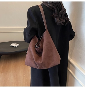 Deep brown suede hobo bag on shoulder featuring premium soft texture and draped folds