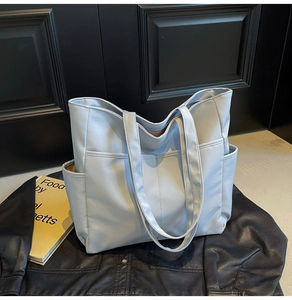 Détail d'un grand sac fourre-tout en nylon bleu clair avec poches sur cuir noir