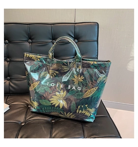 Detail view of large tote bag with tropical leaf pattern and white TOTE BAG text print