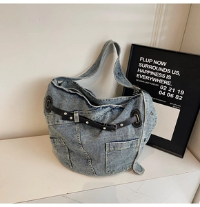 Detail der blauen Jeans-Einkaufstasche mit schwarzen Lederriemen und silbernen Schnallen