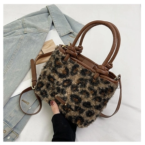 Dettaglio borsa leopardata in ecopelliccia con manico in pelle marrone e placca