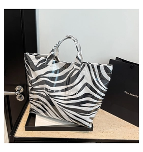 Detailed close-up of a zebra print tote bag with glossy finish and white text lettering