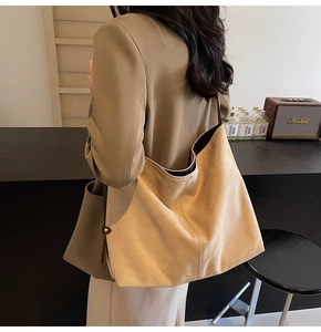Close-up of a large light brown suede tote bag showing texture and side metal buckle details