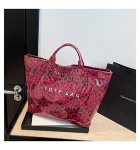 Detail of red leopard print tote bag with white TOTE BAG lettering on a marble table