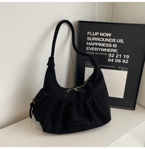 Detail view of black hobo shoulder bag featuring side flap pocket and pleated texture