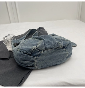 Detail der hellblauen Jeans-Umhängetasche mit Seitentaschen und gewaschenem Denim