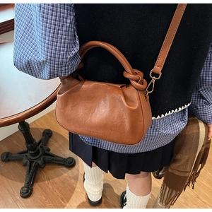 Dettaglio della borsa a mano a pieghe color caramello con logo FASHION & BAGS