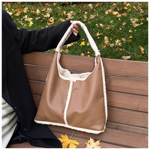 Borsa tote in similpelle marrone con profili in montone sintetico bianco su una panchina
