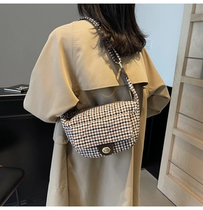 Detail of vintage houndstooth saddle bag with gold metal buckle and brown pattern