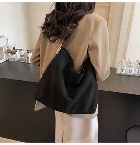 Detail of black suede tote bag featuring a gold metal buckle on a shoulder strap