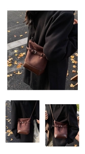 Gros plan d'un sac seau rétro marron mêlant daim et cuir dans un décor de rue automnal