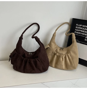 Detail view of khaki and brown crescent bags featuring side utility pockets and embossed logo