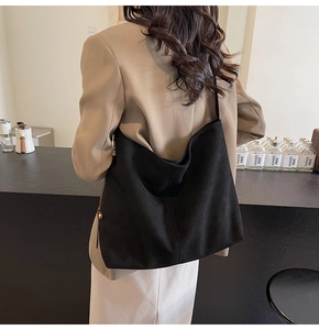 Detail shot of black faux suede hobo bag with brown adjustable shoulder strap