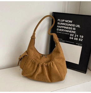 Detail of brown suede hobo bag featuring pleated design and embossed brand logo